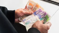 En la foto: Manos sosteniendo dinero colombiano.